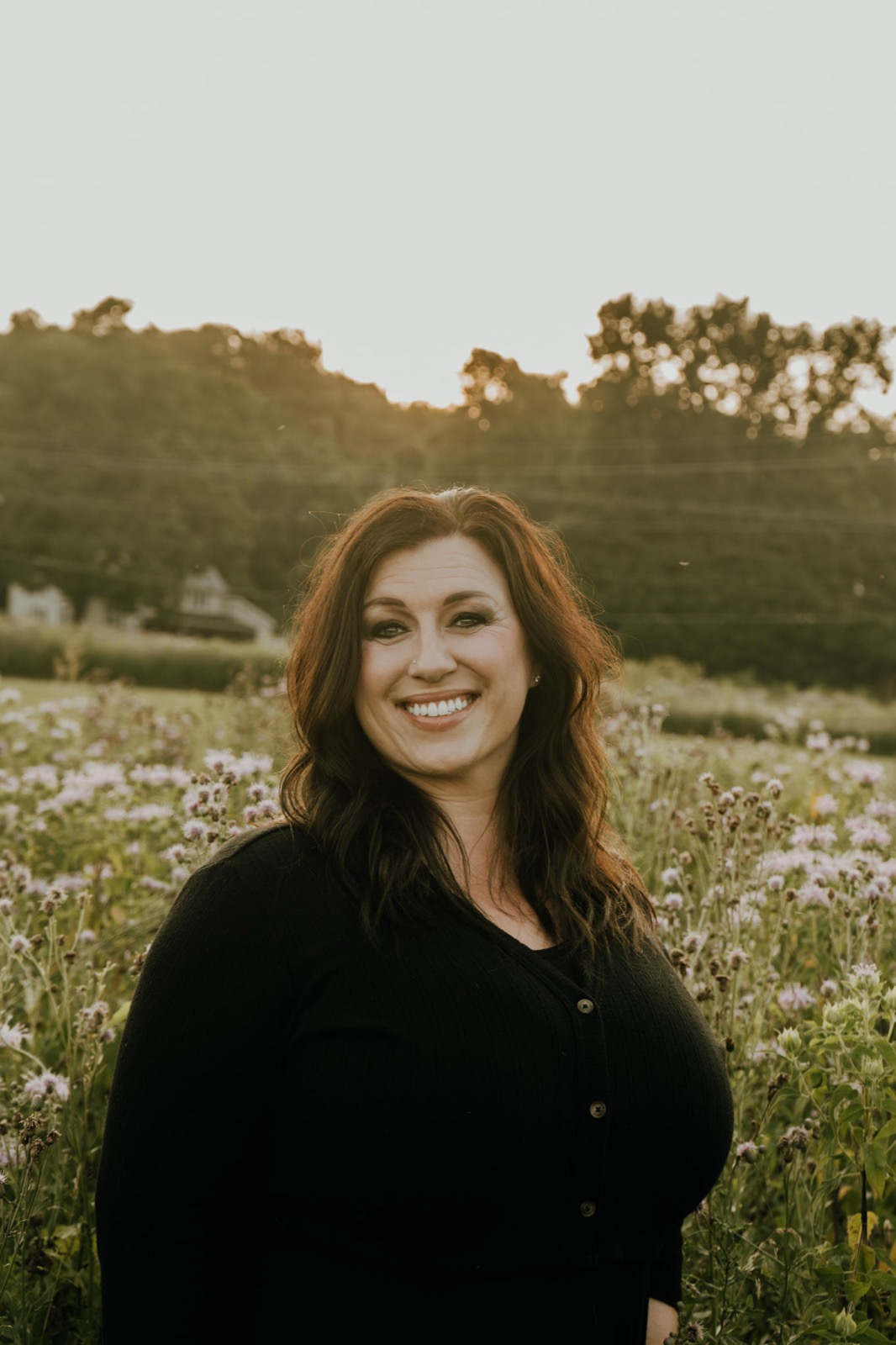 Melissa, Licensed Independent Social Worker, standing in a wildflower field at golden hour